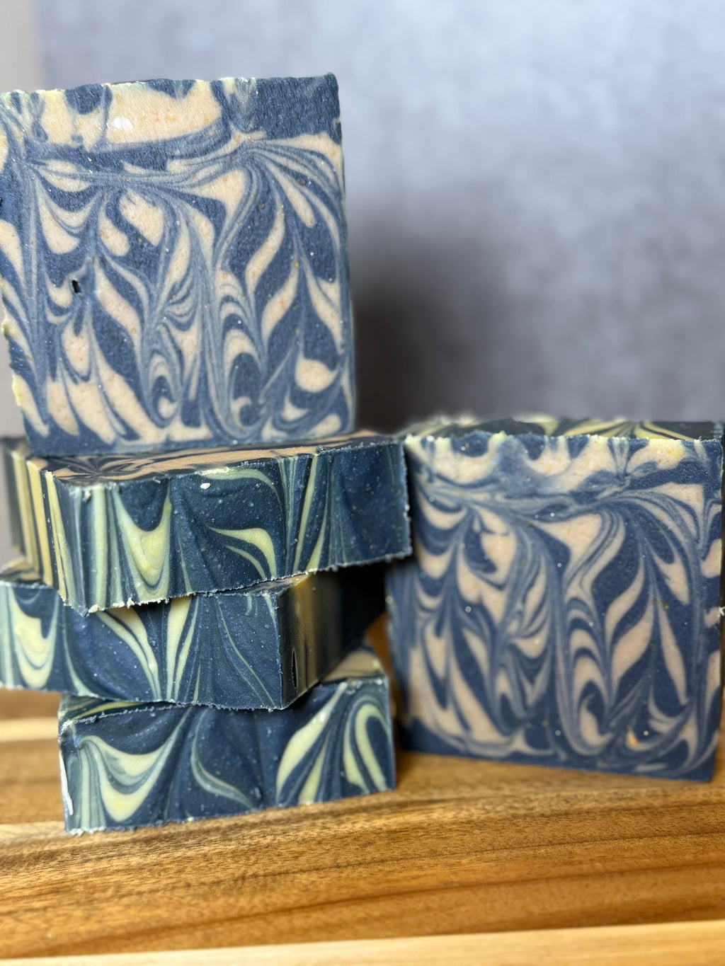 Marbled blue and white soap bars on a wooden surface with a neutral background
