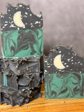 Marbled soap bars with black and green swirls on a wooden surface. Tallow and Goats Milk Soap with colloidal oats and honey.