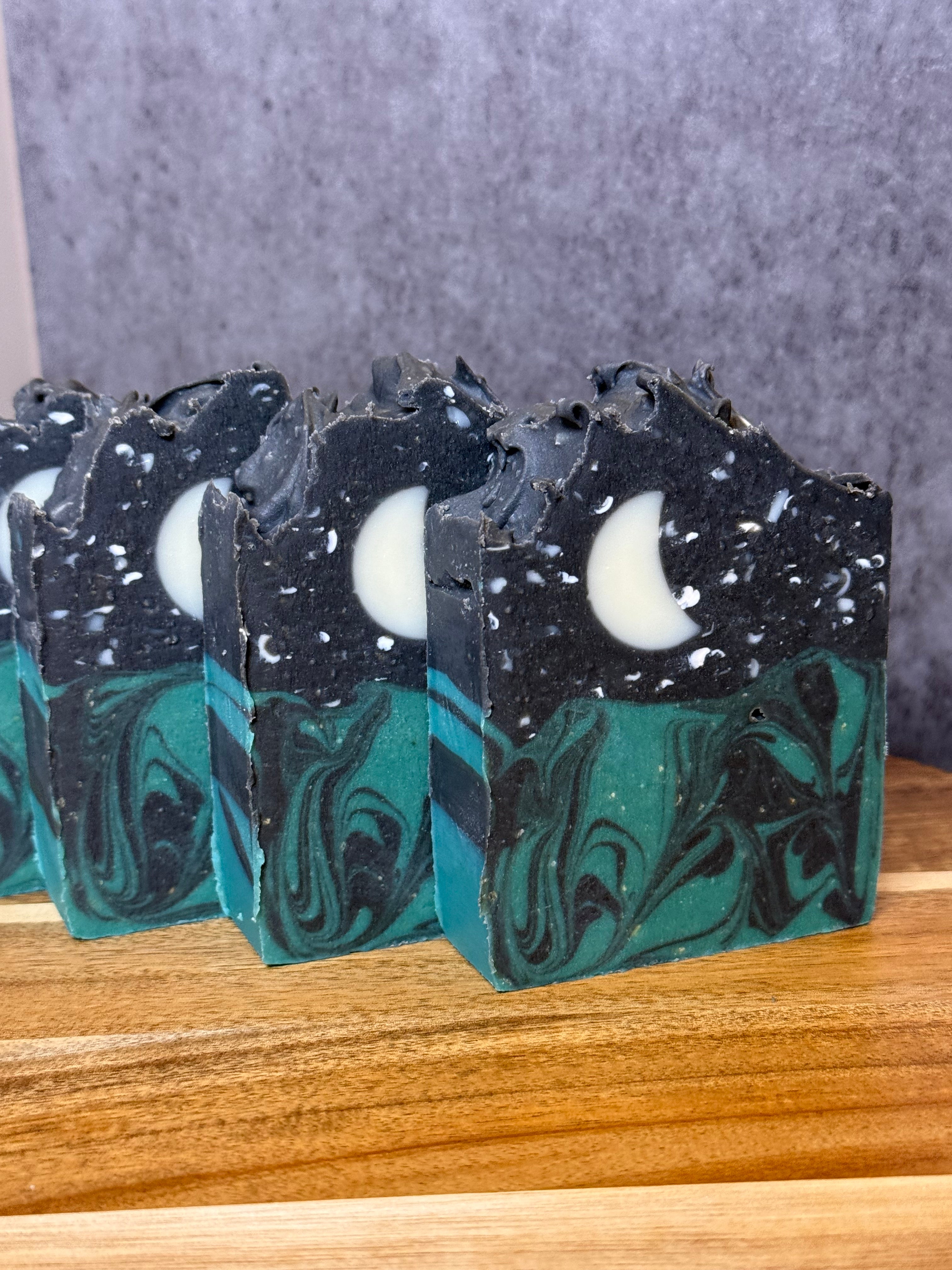 Marbled soap bars with black and green swirls on a wooden surface. Tallow and Goats Milk Soap with colloidal oats and honey.