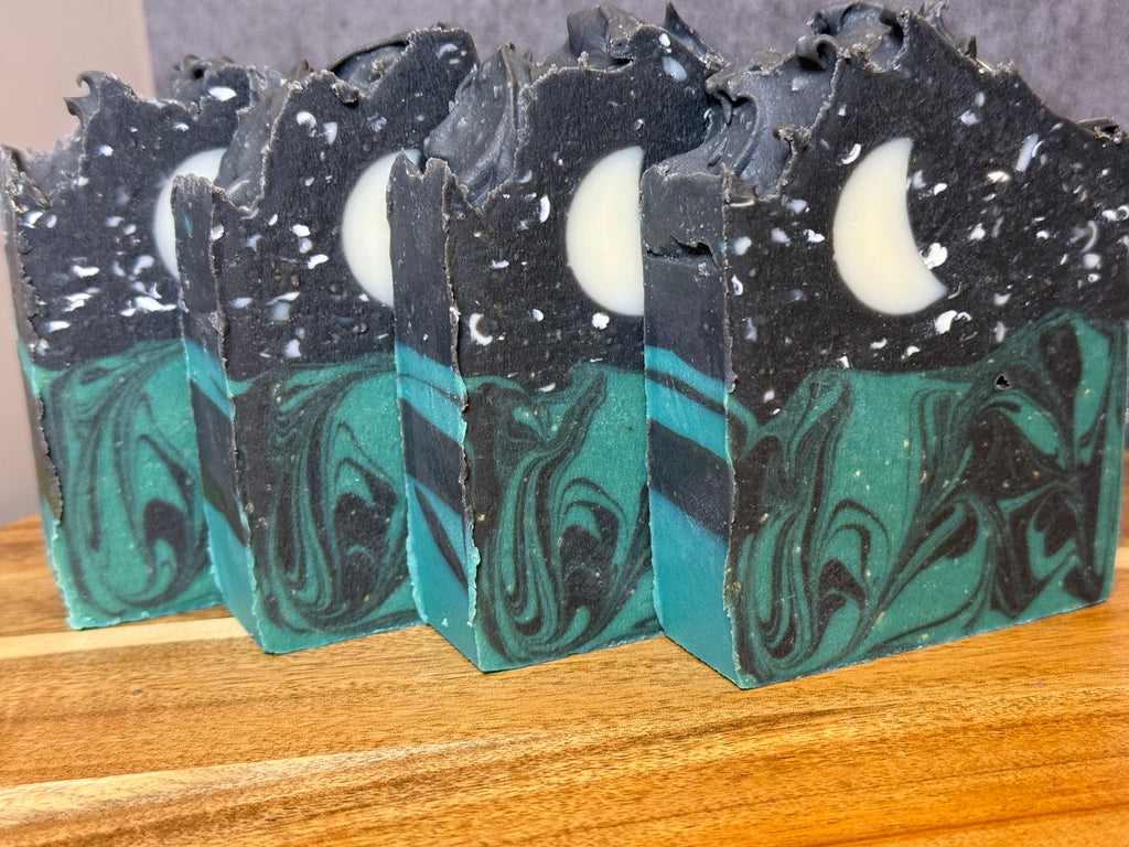 Marbled soap bars with black and green swirls on a wooden surface. Tallow and Goats Milk Soap with colloidal oats and honey.